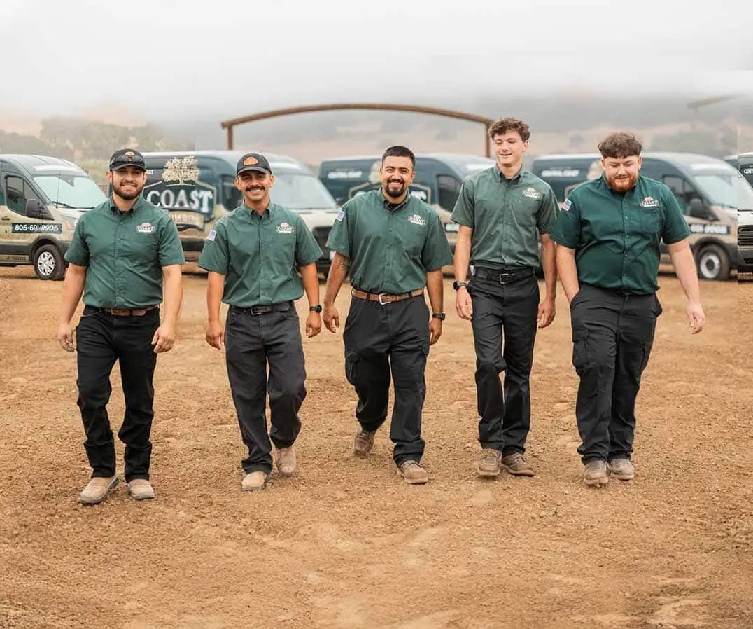 Five Coast Plumbing Solutions technicians in uniform walking in front of the company's service vans